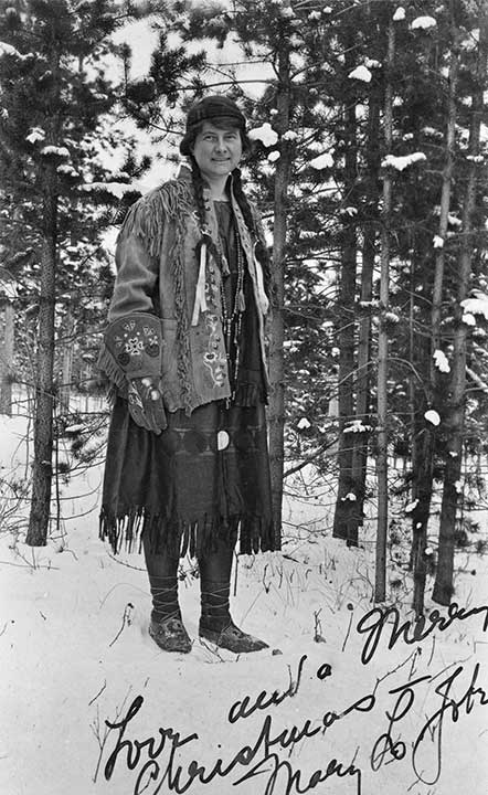Mary Jobe posed in winter amoungst trees in beaded buckskin clothing. n.d.